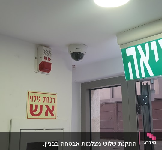 מצלמת אבטחה מותקנת על תקרה ליד שלט יציאה